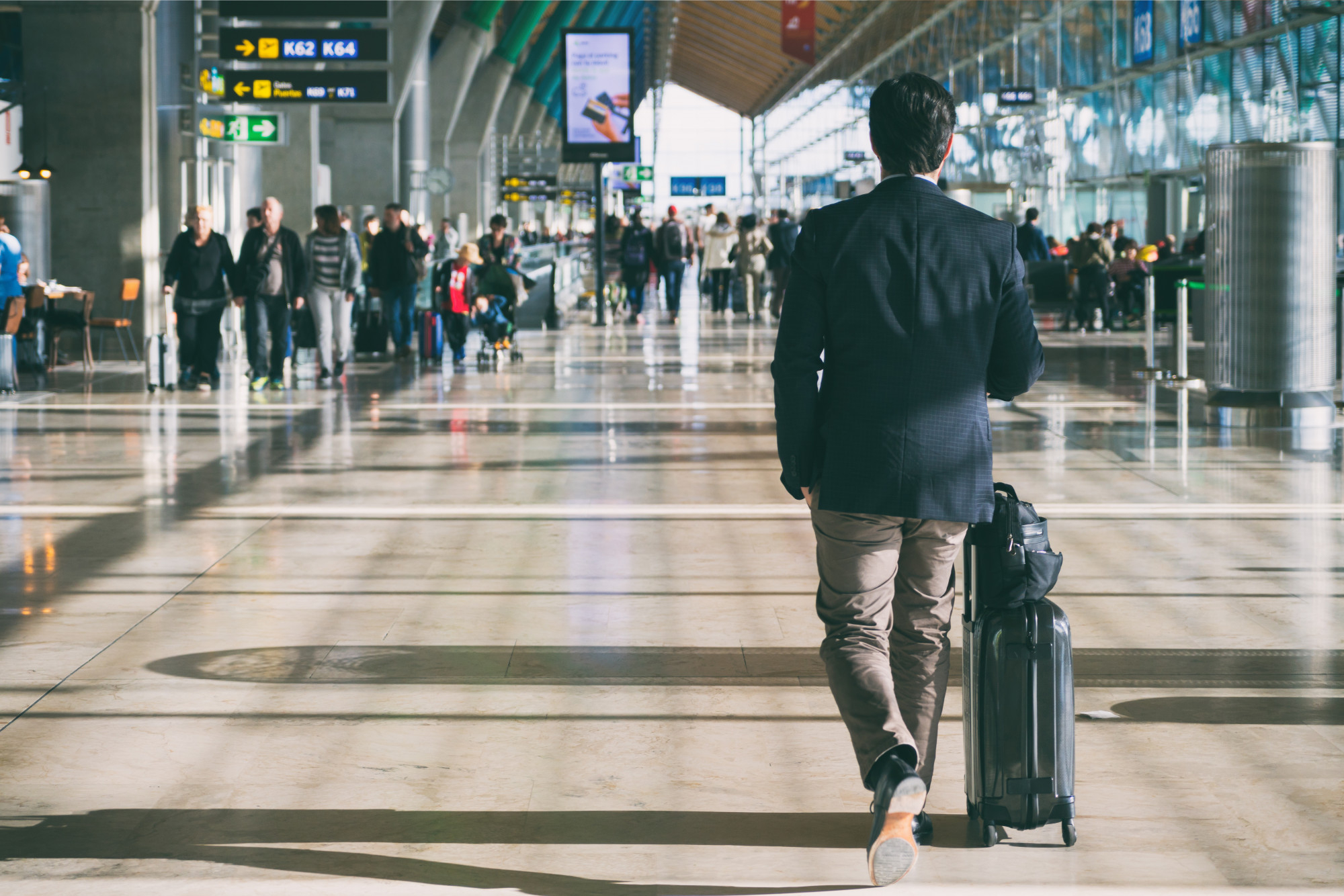 homme-affaires-porter-valise-tout-marcher-par-terminal-depart-passagers